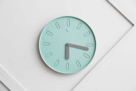 Stylish clock hanging on light wall