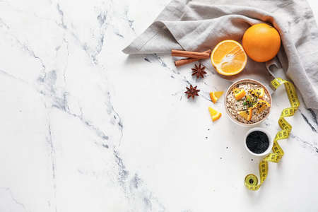 Bowl with raw oatmeal, oranges and chia seeds on light backgroundの写真素材
