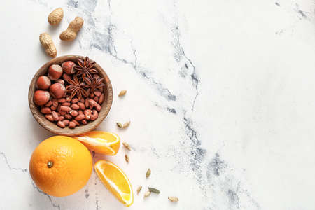Bowl with nuts and oranges on light background