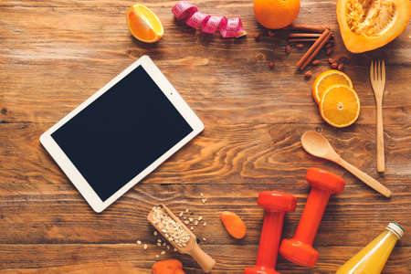 Healthy products, tablet computer and dumbbells on wooden backgroundの写真素材