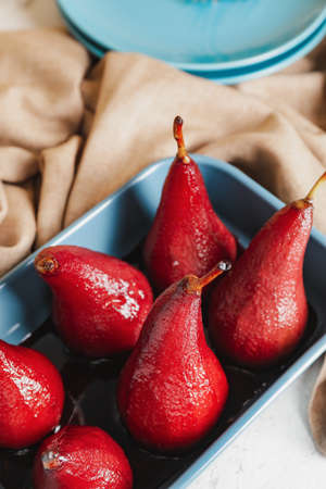 Baking dish with sweet poached pears in red wine on table, closeup