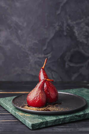 Plate with sweet poached pears in red wine on dark backgroundの写真素材