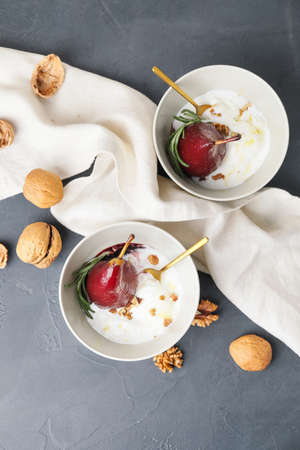 Bowls with sweet poached pears in red wine and ice-cream on dark backgroundの写真素材