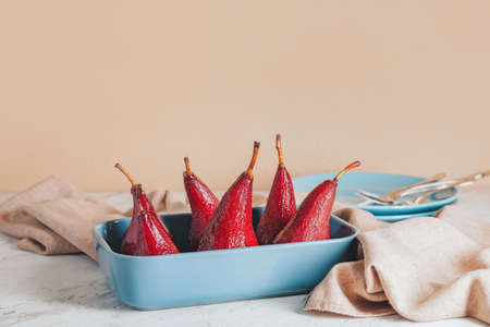 Baking dish with sweet poached pears in red wine on tableの写真素材