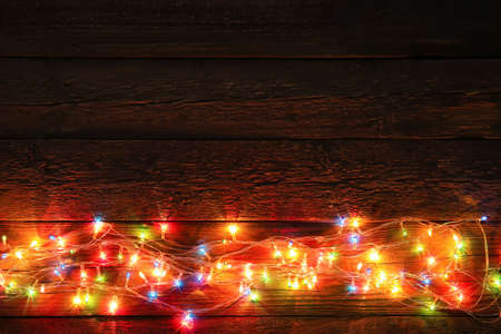 Glowing Christmas lights on dark wooden background