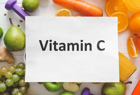 Paper sheet with text VITAMIN C and fresh products on table