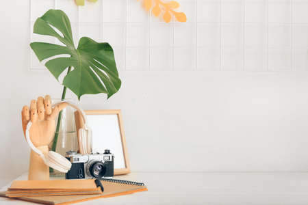 Wooden hand with headphones, photo camera and notebooks on table in roomの写真素材