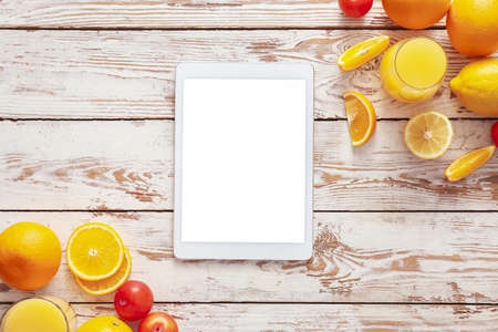 Fresh products and tablet computer on white wooden background. Diet conceptの写真素材