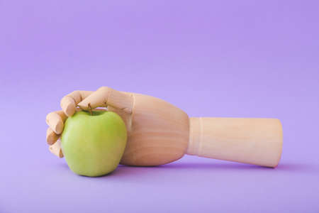 Wooden hand with fresh apple on color background
