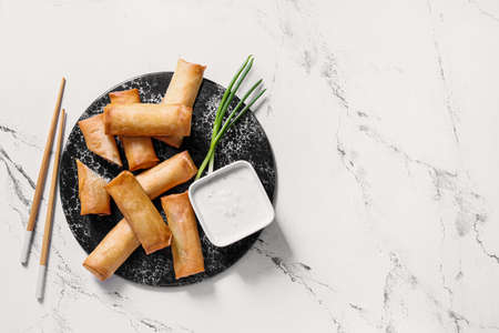 Plate with tasty fried spring rolls and sauce on light backgroundの写真素材