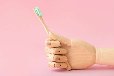 Wooden hand with tooth brush on color backgroundの写真素材