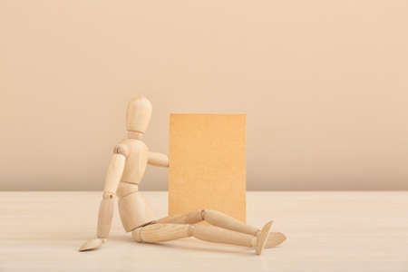 Wooden mannequin with empty paper sheet on color backgroundの写真素材