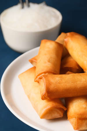 Stand with tasty fried spring rolls on dark background