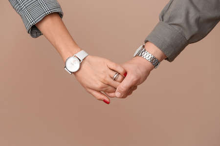 Young couple holding hands on color background
