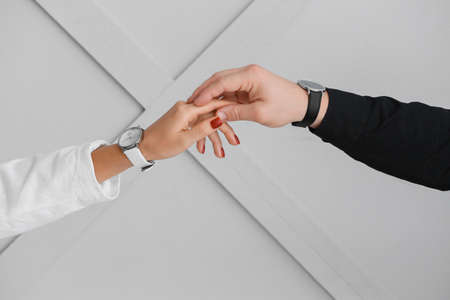 Young couple holding hands on light backgroundの写真素材