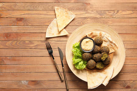 Plate with tasty falafel balls, pita and sauce on wooden backgroundの写真素材