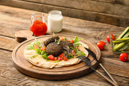 Board with tasty falafel balls, pita and vegetables on wooden backgroundの写真素材