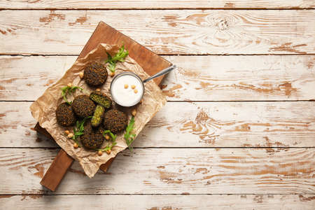 Board with tasty falafel balls and sauce on wooden backgroundの写真素材