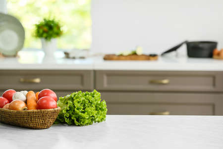 Basket with vegetables on table in modern kitchenの写真素材