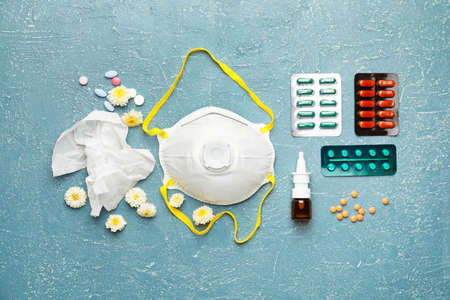 Composition with bottle of drops, flowers and respirator on color background
