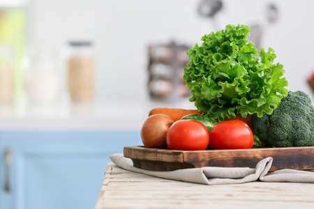 Board with vegetables on table in modern kitchen