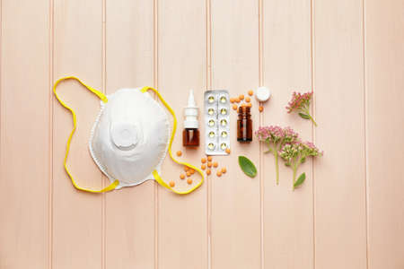 Composition with bottles of drops, flowers and respirator on color wooden background