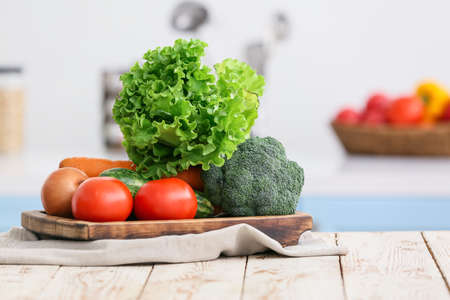 Board with vegetables on table in modern kitchen