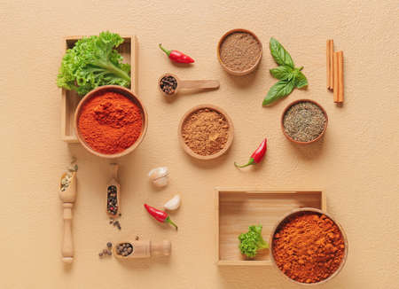 Bowls and scoops with different spices on color background
