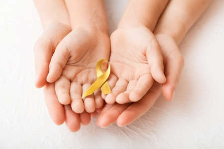 Hands with golden ribbon on white background. Childhood cancer awareness conceptの写真素材