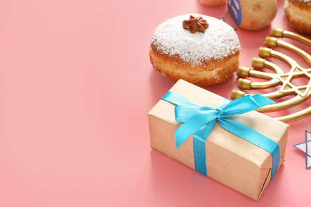 Gift box, donut for Hanukkah and menorah on color backgroundの写真素材