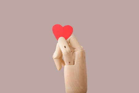 Wooden hand with red heart on color backgroundの写真素材