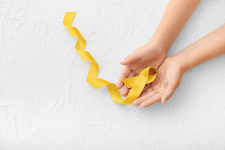 Hands with golden ribbon on white background. Childhood cancer awareness conceptの写真素材