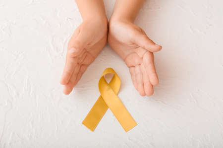 Hands with golden ribbon on white background. Childhood cancer awareness conceptの写真素材