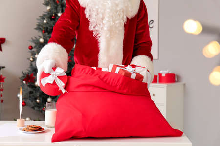 Santa Claus with bag full of Christmas gifts in roomの写真素材