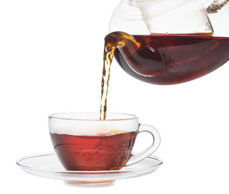 Pouring of hot tea from teapot into cup on white backgroundの写真素材