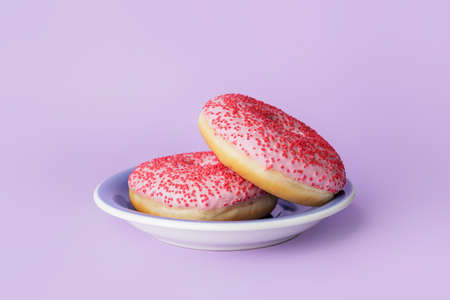 Plate with sweet donuts on color background