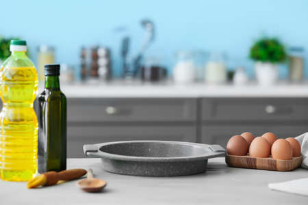 Eggs, oil and baking sheet on table in modern kitchenの写真素材