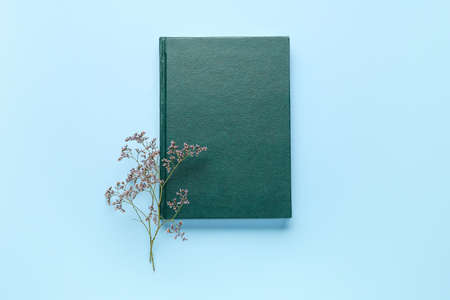 Blank book and flower on color background