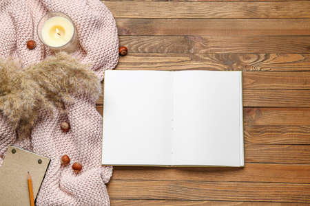 Blank open book, hazelnuts and candle on wooden background
