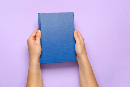 Female hands with blank book on color backgroundの写真素材