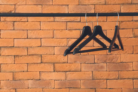 Rack with clothes hangers near brick wallの写真素材