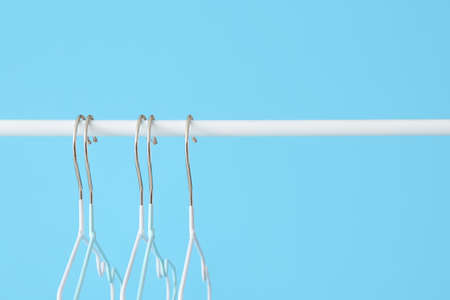 Rack with clothes hangers on color background