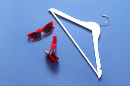 Composition with clothes hanger and sunglasses on color background