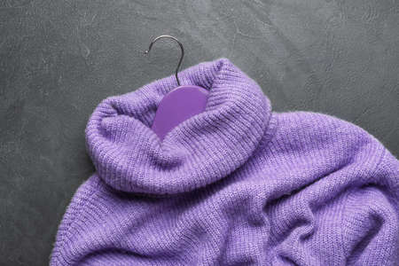 Clothes hanger with sweater on dark background
