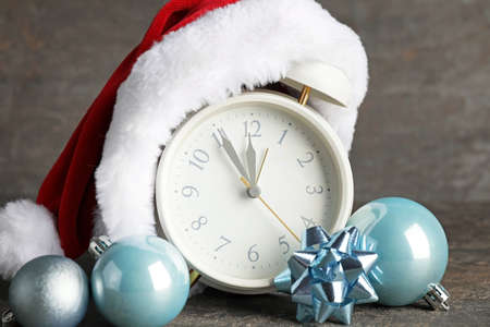 Santa hat with alarm clock and Christmas decor on dark background