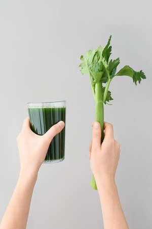 Hands with glass of celery juice on gray backgroundの写真素材
