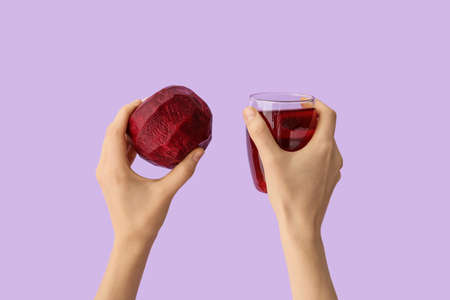 Hands with glass of beetroot juice on color background