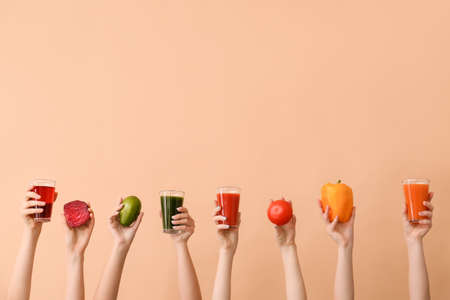 Many hands with glasses of vegetable juices on color backgroundの写真素材