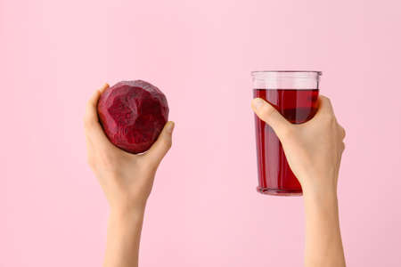 Hands with glass of beetroot juice on color backgroundの写真素材