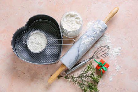 Flour for Christmas bakery and kitchen utensils on color background